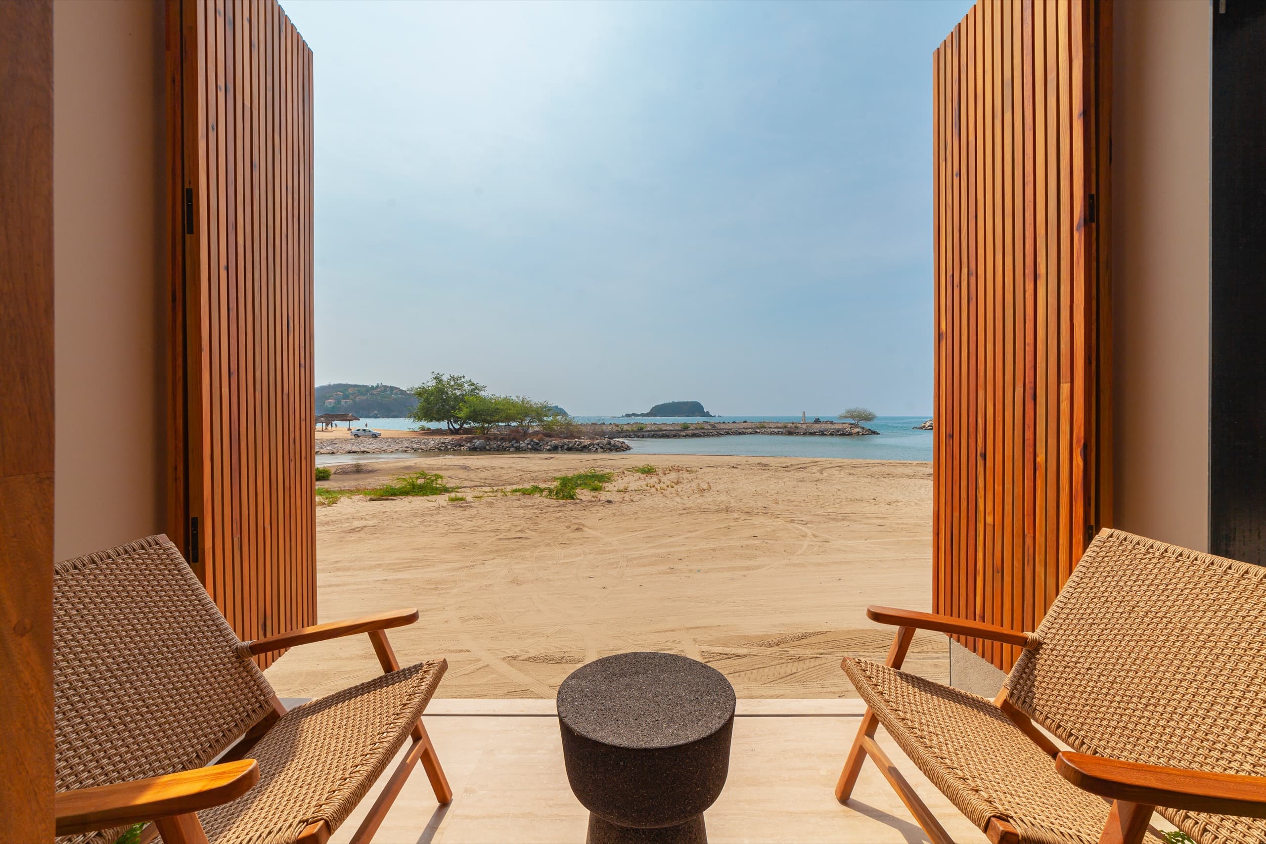 Puertas abiertas que enmarcan la playa desde la terraza
